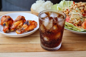 Cola soft drink with ice cubes and papaya salad spicy Thai food