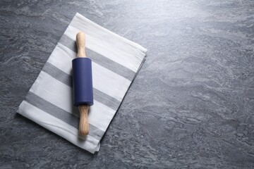 Rolling pin on grey textured table, top view. Space for text