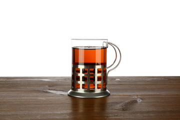 Glass of aromatic tea in holder on wooden table against white background