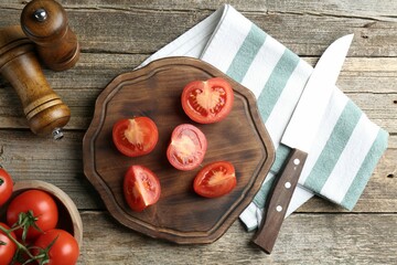Cutting board with tomatoes and knife on wooden table, flat lay