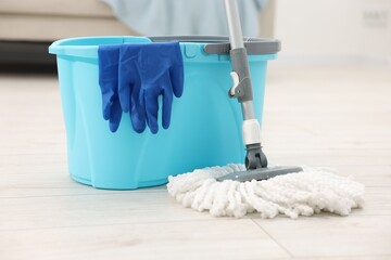 String mop, bucket and gloves on floor indoors
