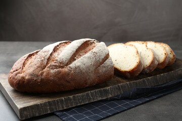 Cutting board with fresh bread on grey table, closeup