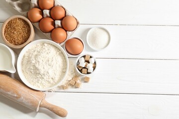 Rolling pin and ingredients for dough on white wooden table, flat lay. Space for text