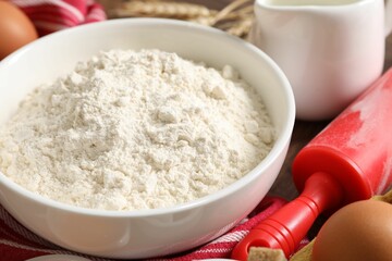 Rolling pin and ingredients for dough on table, closeup