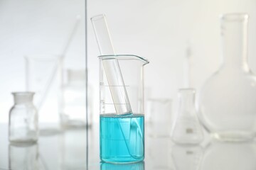 Laboratory glassware on mirror surface against light background