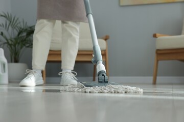 Woman cleaning floor with string mop indoors, closeup