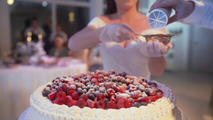 Elegant wedding cake decorated with fresh red berries, delicately sprinkled with powdery white icing sugar, showcasing professional pastry craftsmanship
