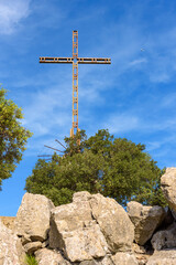 Large metal cross on top of rocky hill in Lluc in Majorca