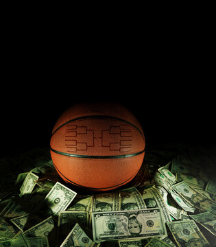 Basketball with march madness tournament bracket on a pile of cash on black
