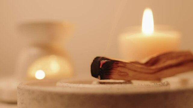 Soothing display featuring a burning Palo Santo stick and lit candle radiating peaceful light. Captures serenity, relaxation, and mindfulness in a warm ambiance. Ideal for wellness, meditation, and ca