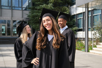 Happy graduates in caps and gowns celebrating outside the university building