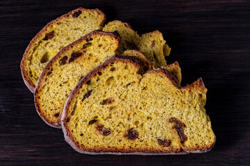 Sliced sweet cornbread with raisins on wooden table, closeup. Arrangement with bakery products. Three yellow slices of bread