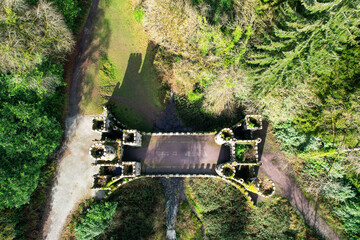 Aerial view of Ballysaggartmore Towers, Ireland, showcasing its striking Gothic gatehouse ruins amid lush woodland