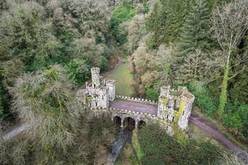 Aerial view of Ballysaggartmore Towers, Ireland, showcasing its striking Gothic gatehouse ruins amid lush woodland