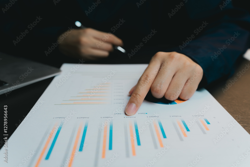 Poster close-up of hand pointing at colorful bar graphs on paper