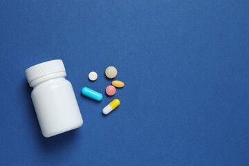White bottle with pills on blue background, top view