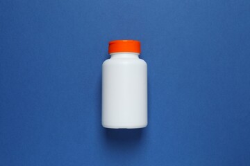 White bottle on blue background, top view