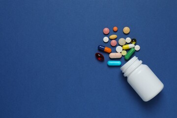 White bottle with pills on blue background, top view