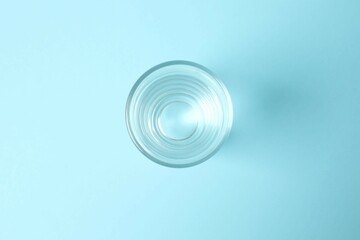 Transparent glass with water on blue background. Drinking clear water in the morning for health