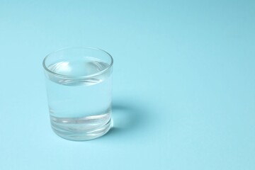 Transparent glass with water on blue background. Drinking clear water in the morning for health