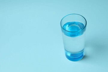 Transparent glass with water on blue background. Drinking clear water in the morning for health