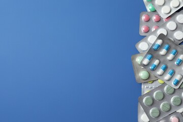 Pills in blister packs on blue background, close up