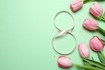 8 March, International Women's Day. Figure eight made of pink ribbon with beautiful tulips on a color background. Space for text