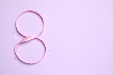 8 March, International Women's Day. Figure eight made of pink ribbon on a color background. Space for text