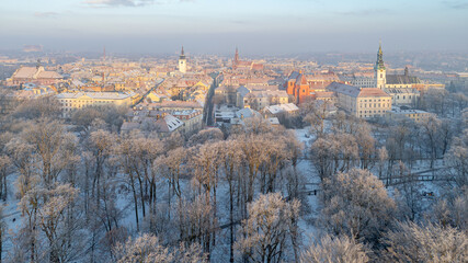 winter city landscape from a drone. aerial view of snowy city streets, snowy roofs of buildings on a frosty morning. delicate quiet frosty sunrise over the city and city park. trees in the snow