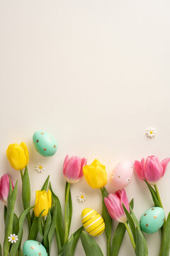 Bright vertical yellow and pink tulips with pastel decorative easter eggs and daisy flowers create a spring-themed composition on a plain background