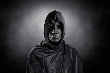 Scary figure with hooded cloak over dark misty background with clipping path