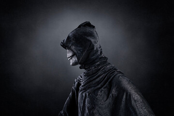 Scary figure with hooded cloak over dark misty background with clipping path