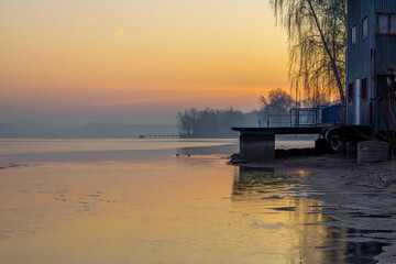 dirty winter lake beach at sunrise. orange sunrise over the retention water reservoir