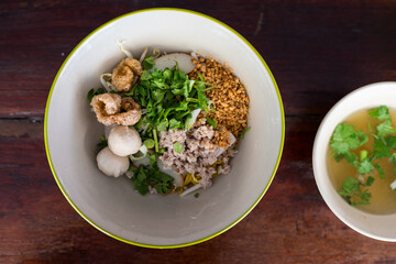Thai noodle, egg yellow noodles topping with minced pork, peanuts, crispy pork rinds and fish meatball. Popular noodle in Thailand. Top view