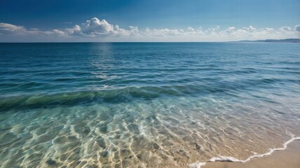 Serene view of ocean waves meeting the sky on a clear sunny day with soft clouds in the background