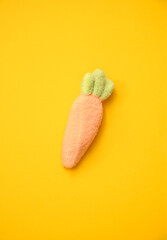 Soft-textured marshmallow carrot with green leaves on a bright yellow background. Ideal for festive decor, cards, and branding.