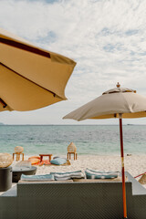 A relaxing beachfront setup in Koh Lipe, Thailand, featuring umbrellas, cushions, and ocean views. A serene tropical escape with cozy seating and a picturesque seaside atmosphere