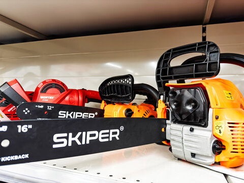 Various Skiper chainsaws are neatly laid out on a shelf in a hardware store, showcasing different models and designs suitable for cutting wood and landscaping. Belarus, Gomel, February 2025