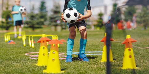 Football training camp for school kids. Children playing soccer training games outdoors. Kids running at obstacle course