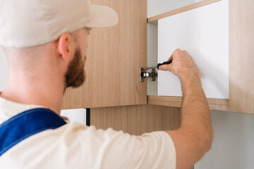 Professional handyman installing cabinet hardware in modern apartment kitchen