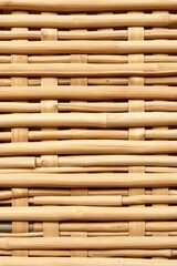 Close-up of a meticulously woven bamboo surface showcases intricate craftsmanship and light brown texture.