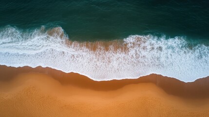 Aerial view captures a serene beach scene with gentle waves rolling in towards the sandy shore, highlighting the tranquil beauty of nature.