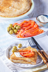Pancakes with gravlax, cottage cheese and olives. A traditional dish for Maslenitsa or Carnival.