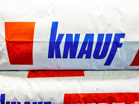 Stacked Knauf building materials displayed in a warehouse, showing colorful packaging and clear branding. Belarus, Gomel, February 2025