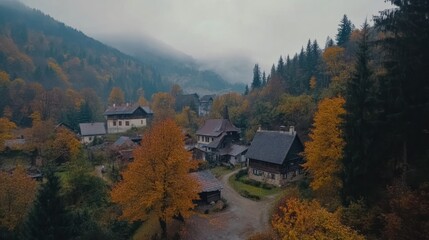 Fototapeta premium Autumnal Village Nestled In Misty Mountain Valley