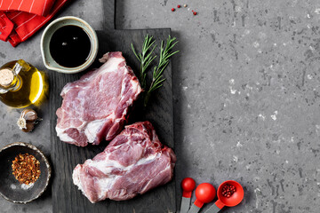Raw pork steak on a cutting board on a dark background.