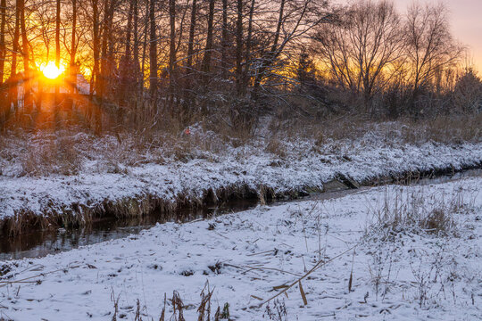 beautiful winter sunset over the river. winter morning over the water. orange sun rays in nature. snow in nature. wild water birds swimming on the river, ducks.