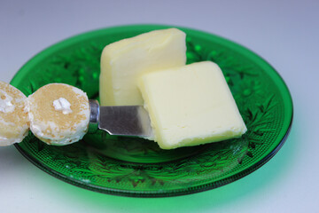 close-up of a pat of butter on a decorative plate with butter knife isolated on a white background....