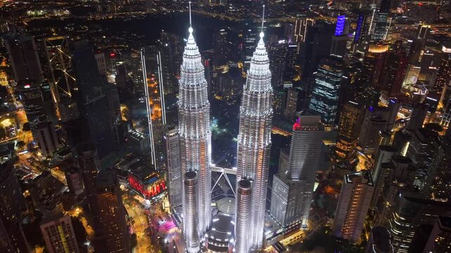High angle aerial drone video of Petronas Towers in city center of Kuala Lumpur, Malaysia brightly illuminated in the night