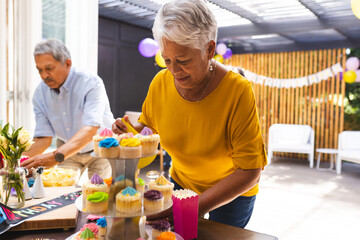 Decorating cupcakes, grandmother at diverse family birthday party, celebrating with joy